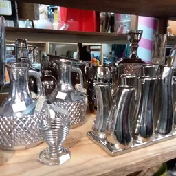 Zilverkleurige serviezen, kannen en tafeldecoraties op een houten display
