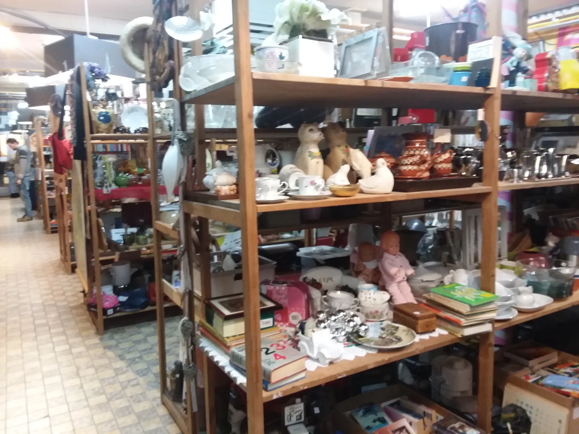 Houten stellingen met diverse huishoudelijke spullen, decoratiestukken en gebruiksartikelen in een kringloopwinkel