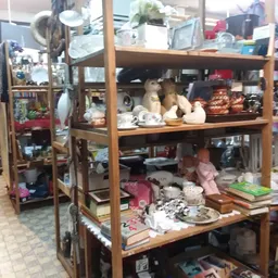 Houten stellingen met diverse huishoudelijke spullen, decoratiestukken en gebruiksartikelen in een kringloopwinkel