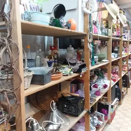Houten stellingen met diverse huishoudelijke artikelen, decoratie en tweedehands spullen in een kringloopwinkel