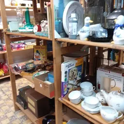 Houten stellingen met uitgestalde serviesgoed, vazen en huishoudelijke artikelen in de winkel
