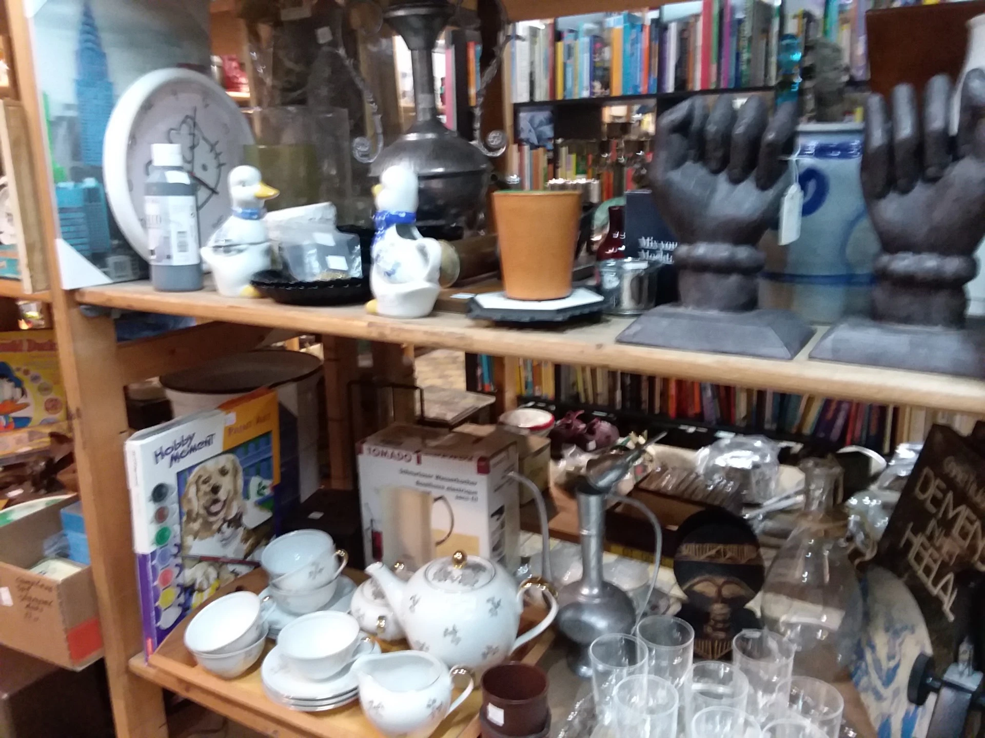 Stellingen met serviesgoed, glazen, boeken en huishoudartikelen in een kringloopwinkel