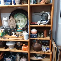 Houten stellingkast met diverse gebruiksartikelen: servies, beeldjes, camera's, huishoudelijke spullen