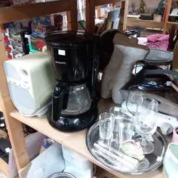 Diverse huishoudelijke artikelen op een plank: koffiezetapparaat, pannen, glazen en ander servies