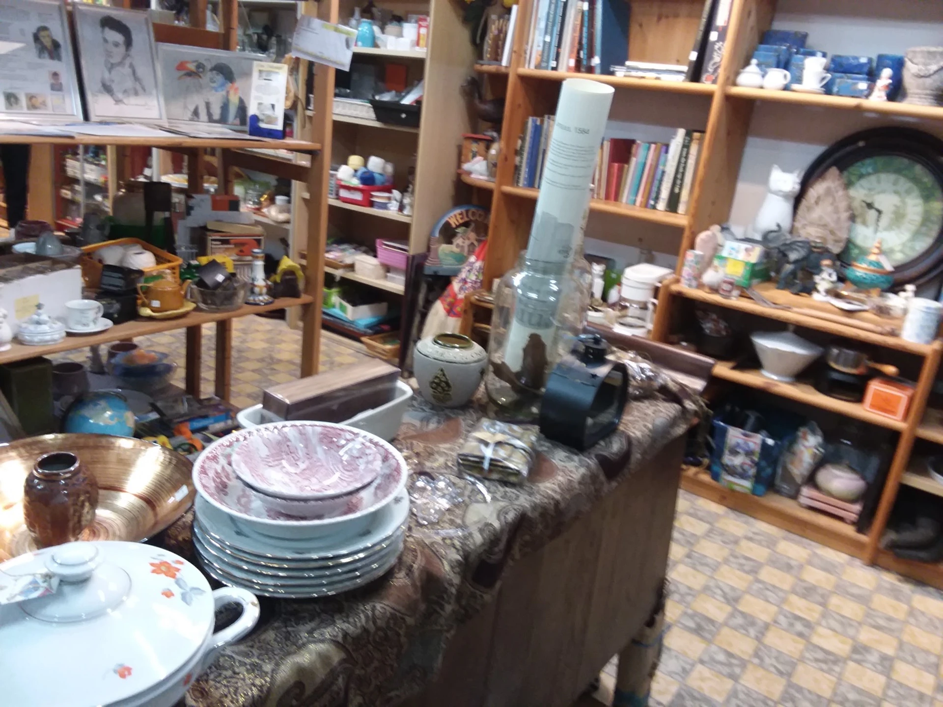 Servies en huishoudelijke artikelen uitgestald op een tafel in een kringloopwinkel