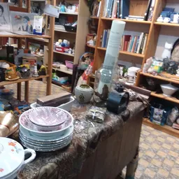 Servies en huishoudelijke artikelen uitgestald op een tafel in een kringloopwinkel