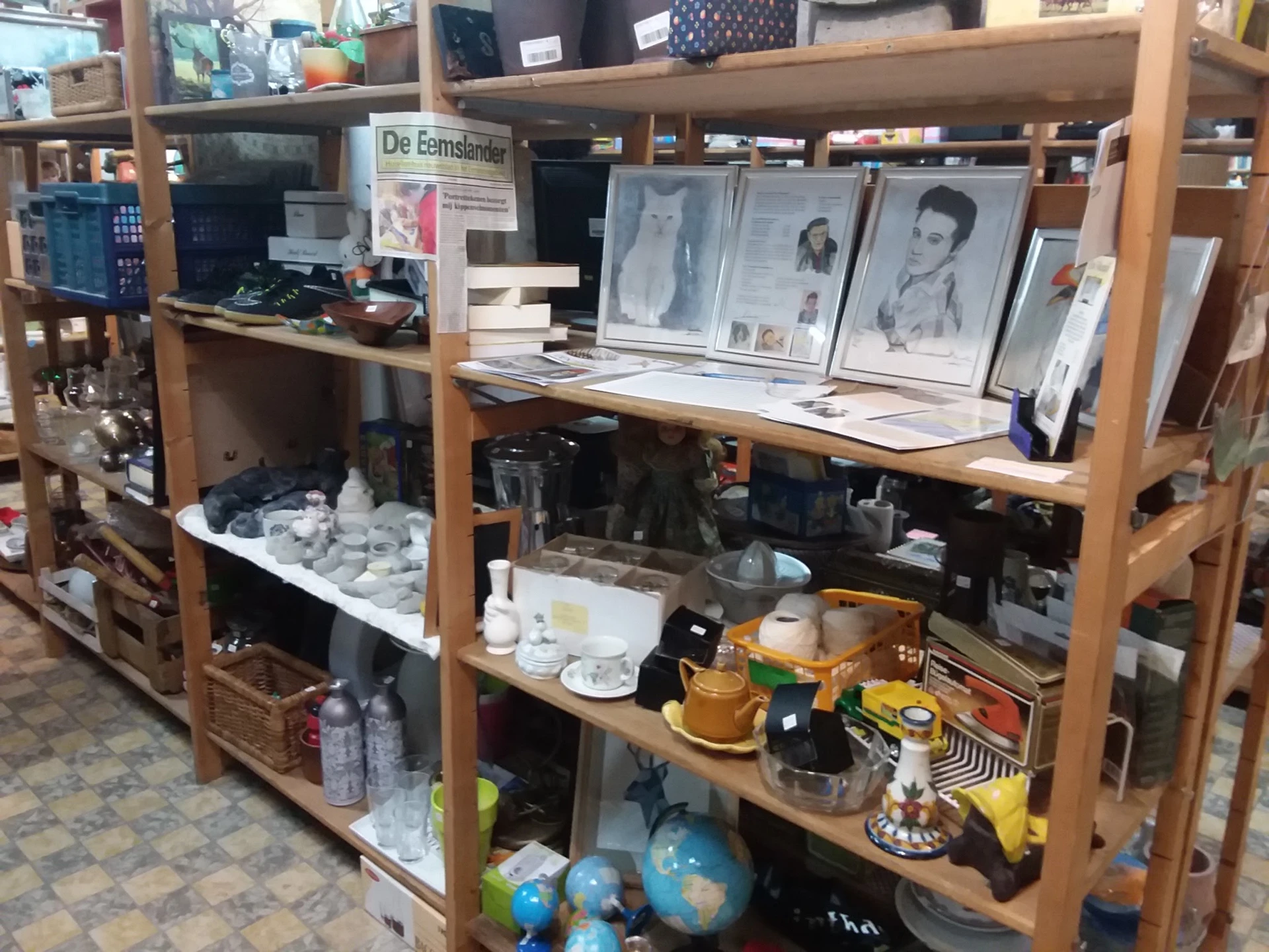 Houten stellingen met diverse tweedehands artikelen zoals porselein, decoratie, boeken en huishoudspullen