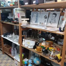 Houten stellingen met diverse tweedehands artikelen zoals porselein, decoratie, boeken en huishoudspullen