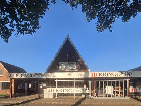 Voorgevel van JD Kringloop met bakstenen gevel, groot puntdak en zichtbare winkelnaam op de pui