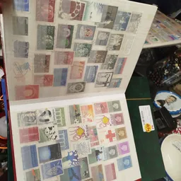 Verzameling losse postzegels uit verschillende landen en periodes, gerangschikt in een fotoalbum