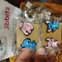 Close-up van vier gekleurde kinderhangers in roze en blauw met dierenvormen, verpakt in plastic op kartonnen kaartjes