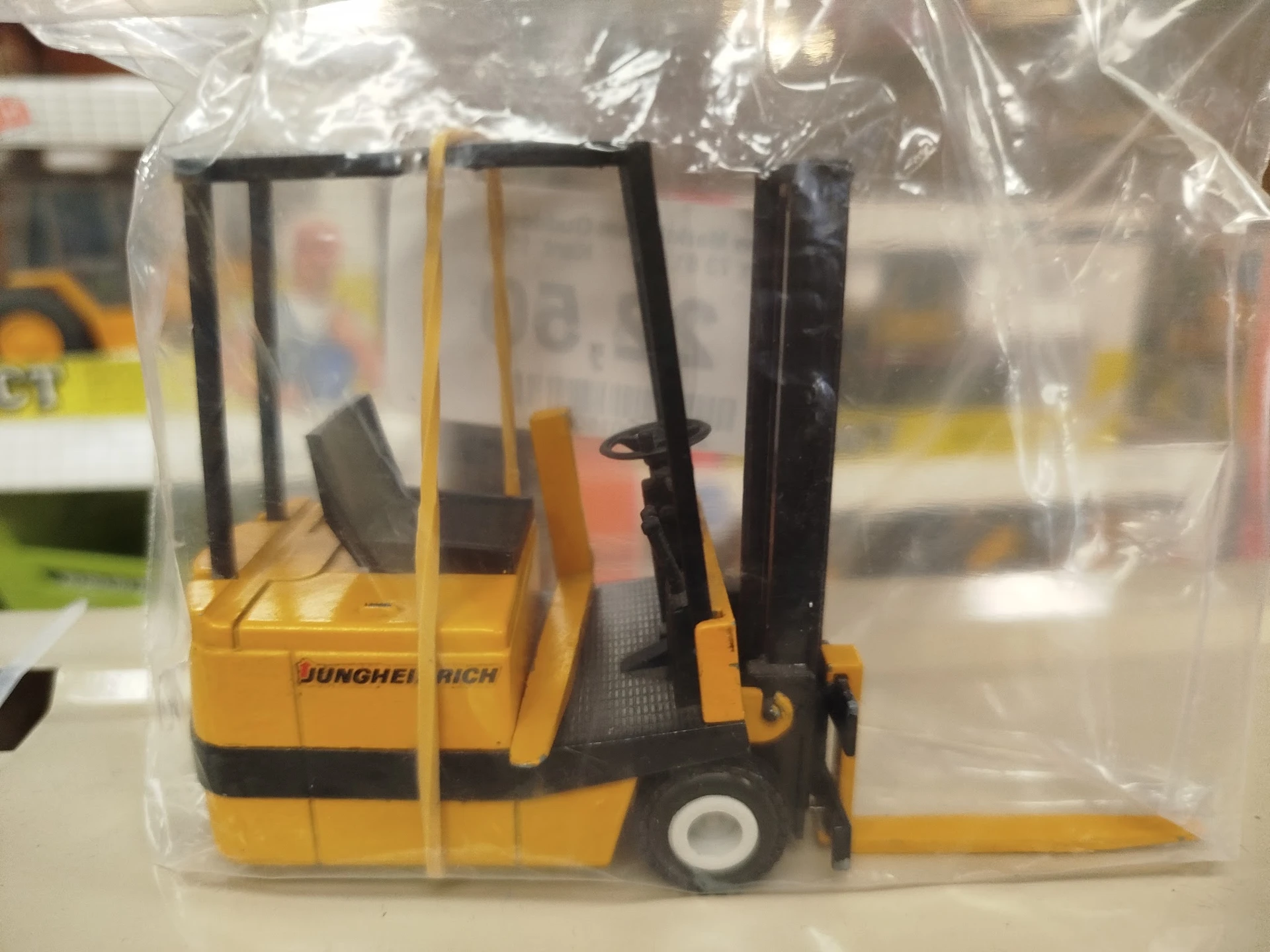 Miniatuurnmodel van een gele heftruck met zwart mast, verpakt in plastic