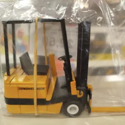 Miniatuurnmodel van een gele heftruck met zwart mast, verpakt in plastic