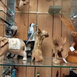 Glazen vitrine met diverse houten beeldjes en decoratieve objecten zoals olifant, vogels en andere kunstvoorwerpen