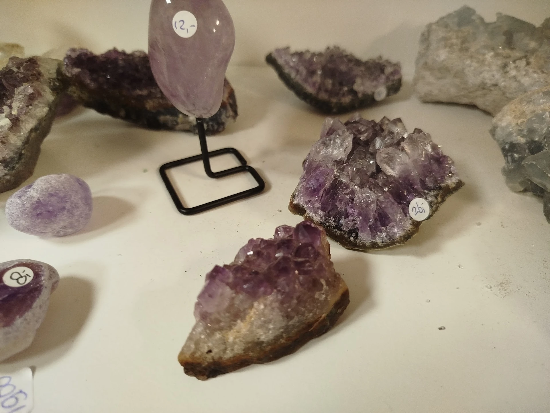 Uitstalling van kristallen en mineralen, waaronder amethist, op displays en standaards