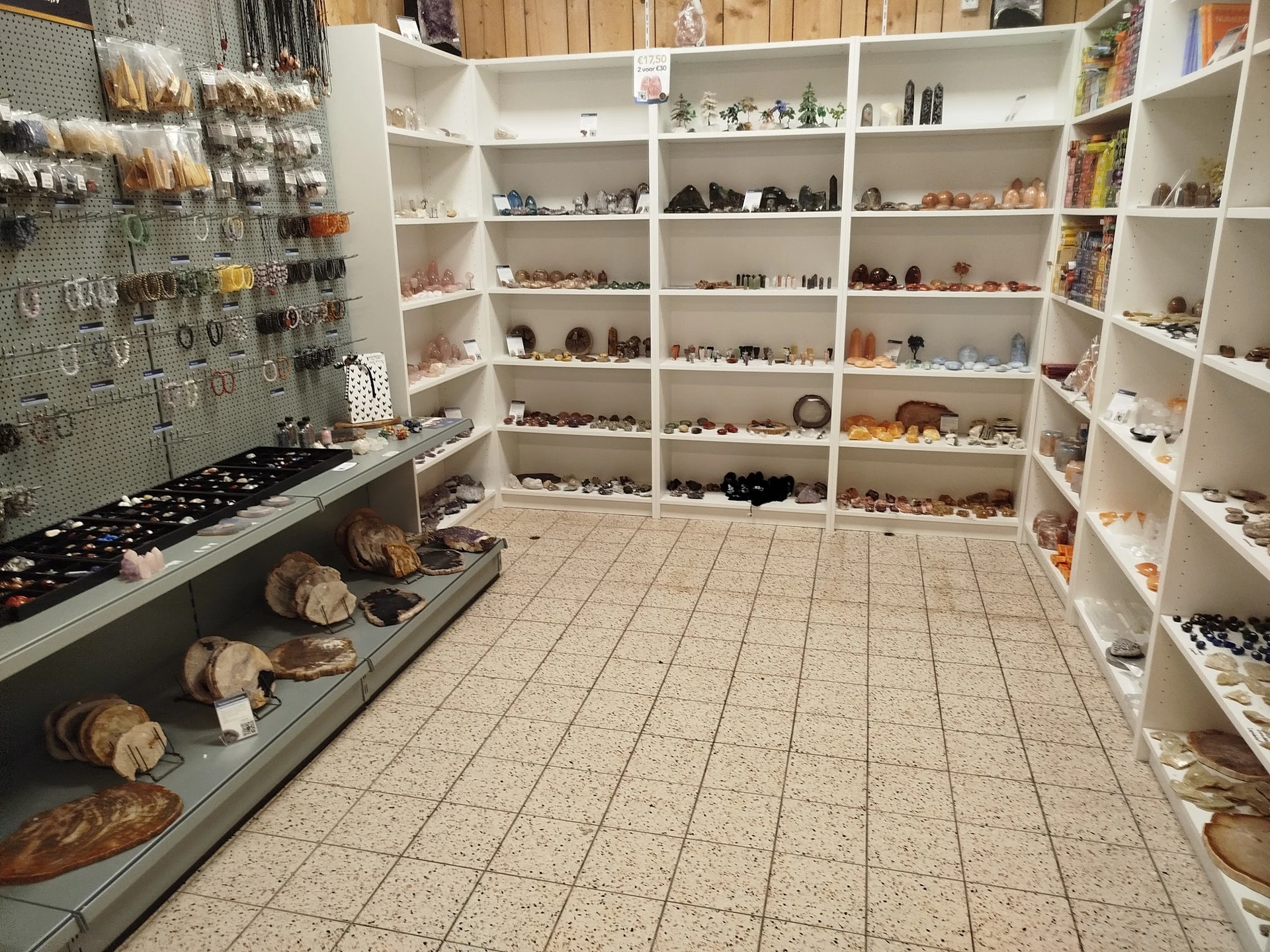 Winkelinterieur met witte stellingen vol decoratieve artikelen, souvenirs en verzamelobjecten