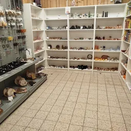 Winkelinterieur met witte stellingen vol decoratieve artikelen, souvenirs en verzamelobjecten