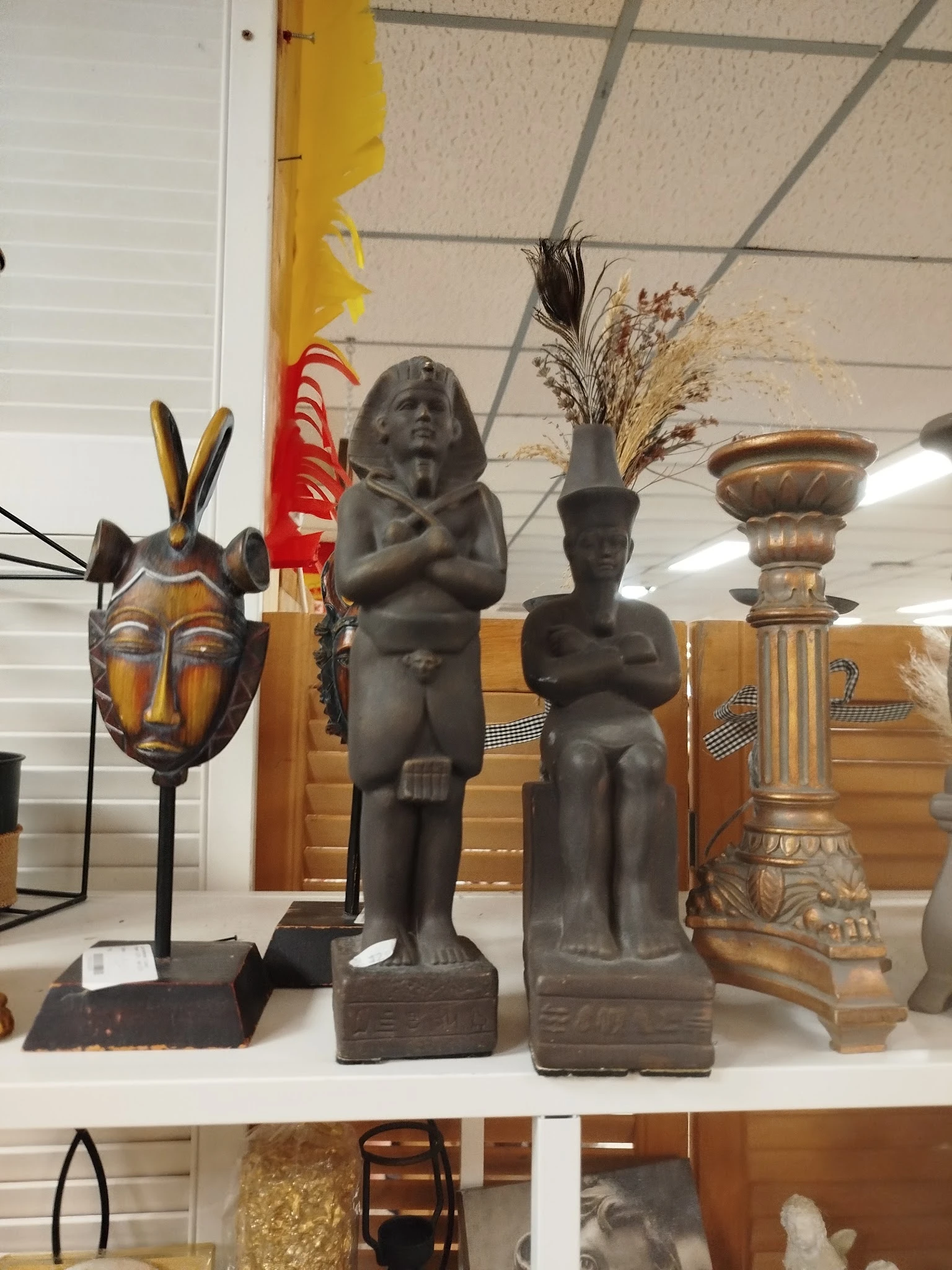 Uitstalling met African artwork: houten beelden, maskers en decoratieve urnen op voet