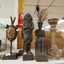 Uitstalling met African artwork: houten beelden, maskers en decoratieve urnen op voet