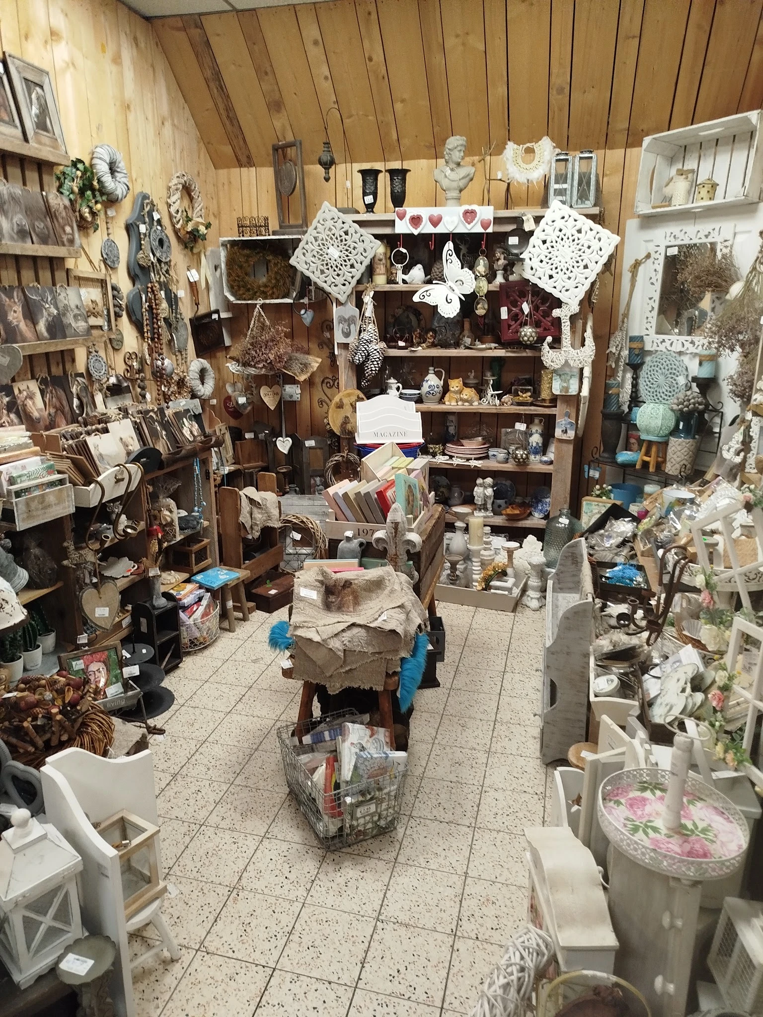 Overzicht van het interieur van een kringloopwinkel met stellingen, dozen en uitgestalde spullen