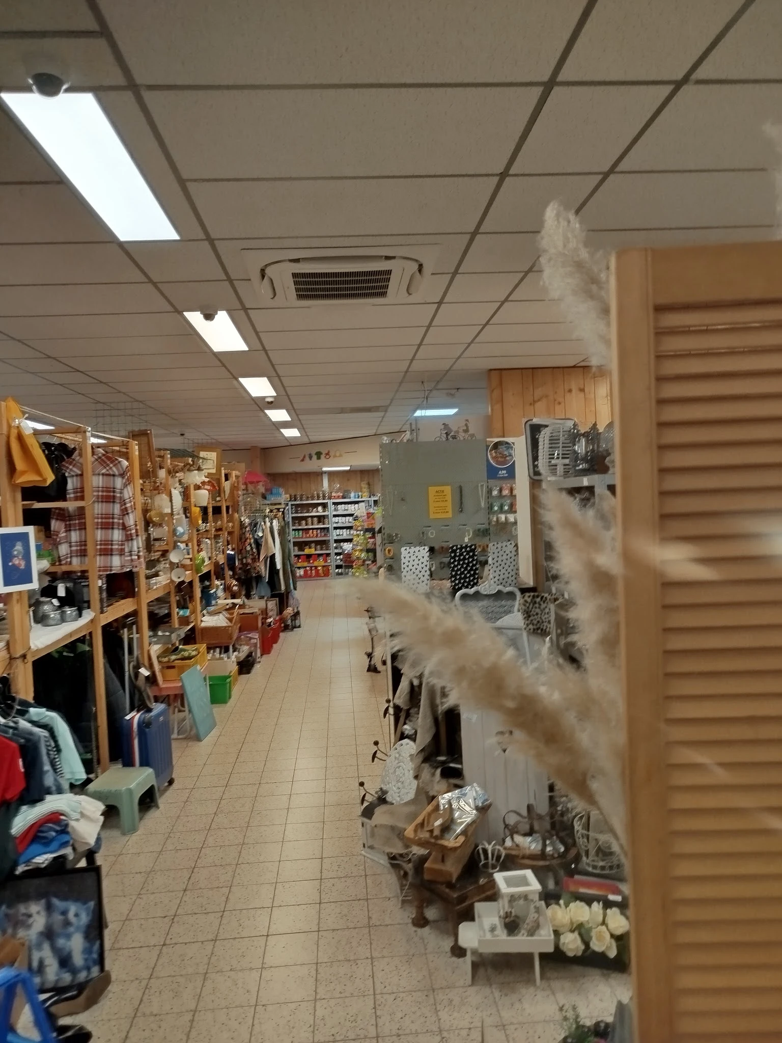 Winkelvloer van kringloopwinkel met houten stellingen, opgestelde artikelen en een wat mistige/stoffige atmosfeer