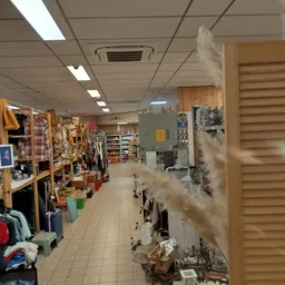 Winkelvloer van kringloopwinkel met houten stellingen, opgestelde artikelen en een wat mistige/stoffige atmosfeer