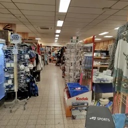 Binnenaanzicht van kringloopwinkel met stellingen, kleding aan hangers, boeken en huishoudartikelen langs de wanden