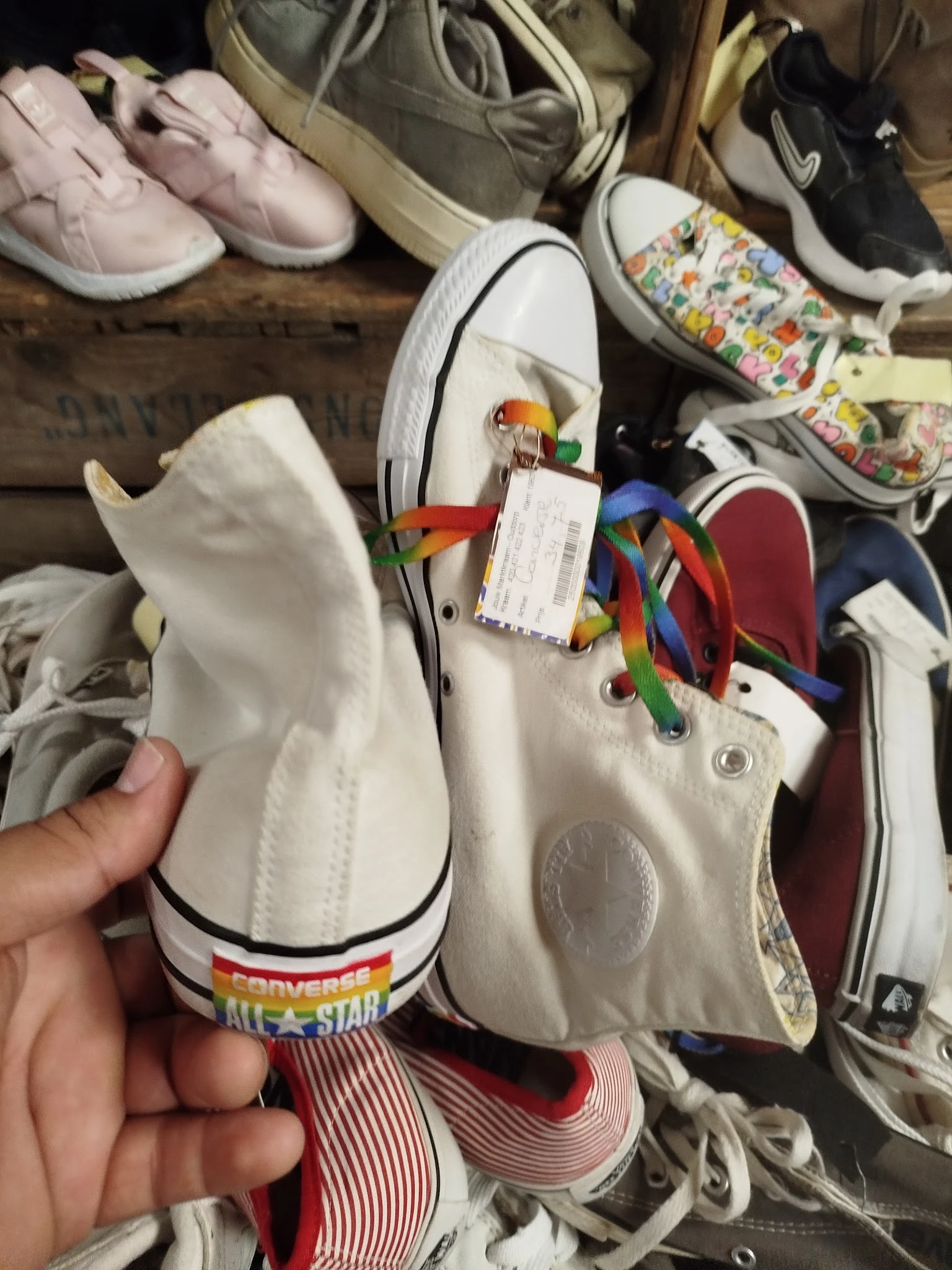 Witte sneaker met kleurrijke papegaai-decoratie en gekleurde veter, close-up van schoen in hand