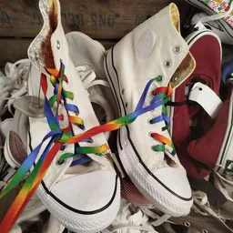 Twee witte sneakers met regenboog gekleurde veters, close-up van schoenenpaar