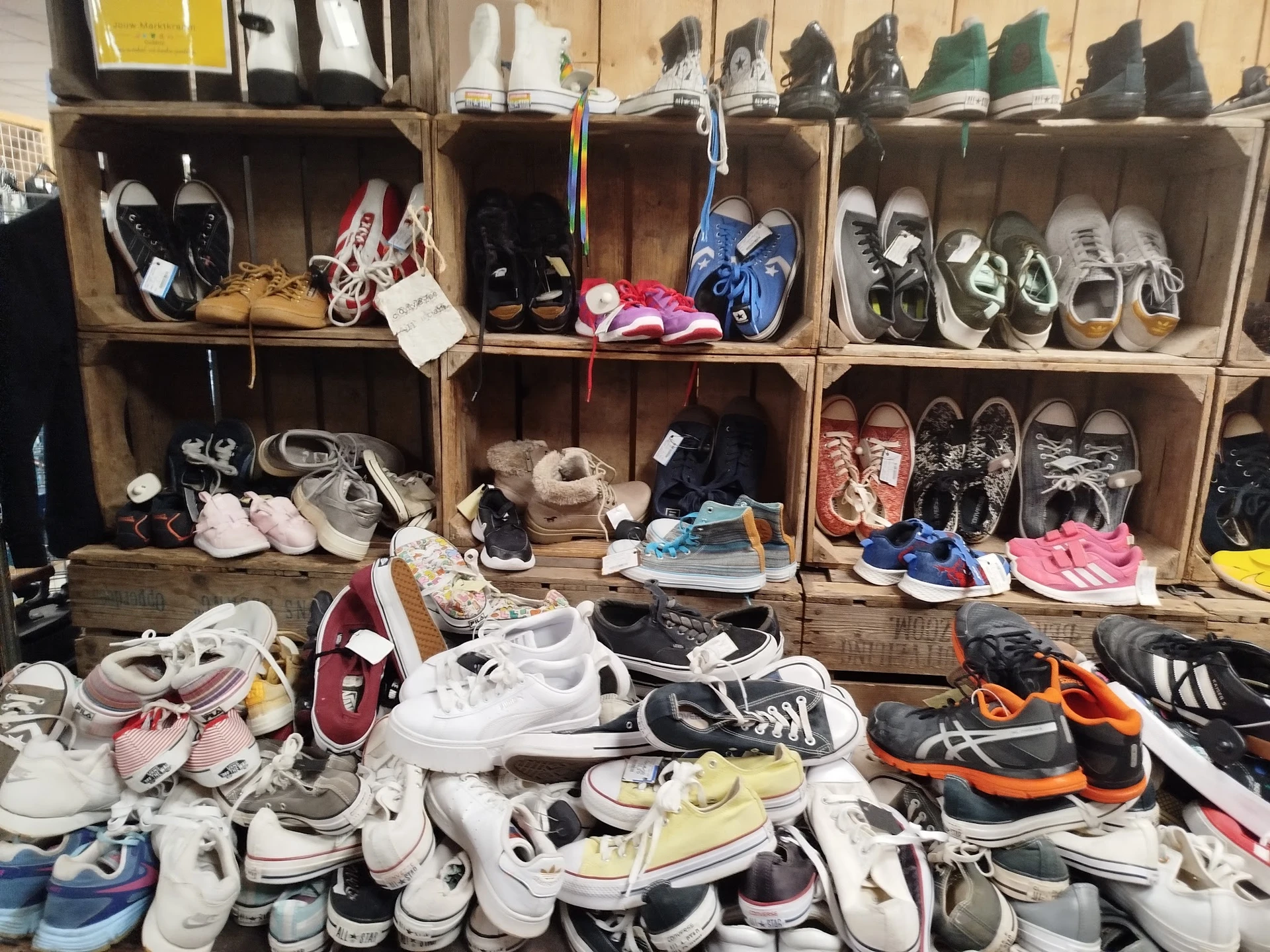 Uitgestalde tweedehands schoenen en sneakers op stellingen en op de grond in de kringloopwinkel