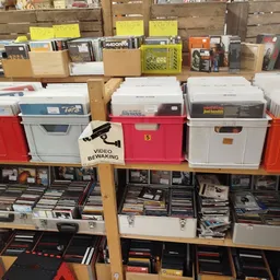 Planken met dvd's, cd's en ander media in dozen en bakken georganiseerd in de winkel