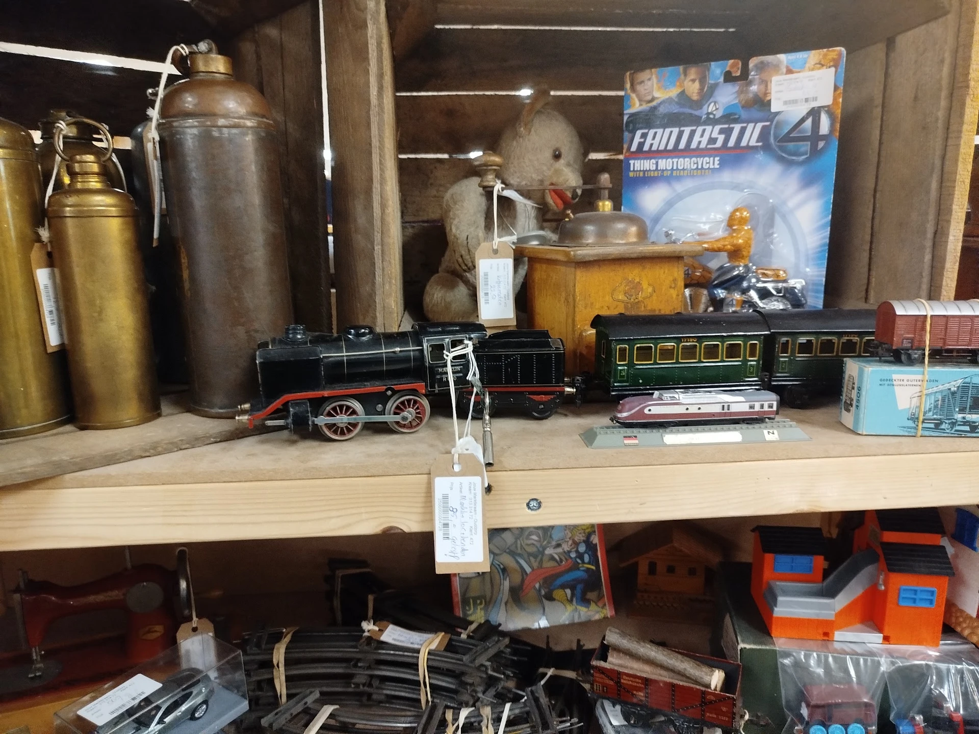 Verzameling vintage speelgoedtreinen, metalen kannen en decoratieve items op een winkelplank