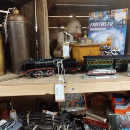 Verzameling vintage speelgoedtreinen, metalen kannen en decoratieve items op een winkelplank