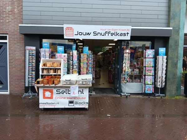 Winkelgevel van tweedehands winkel met etalage vol spullen en reclameborden