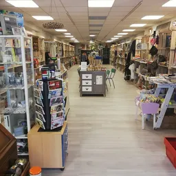Winkelvloer van kringloopwinkel met stellingen vol artikelen, tafels met spullen en overhead verlichting