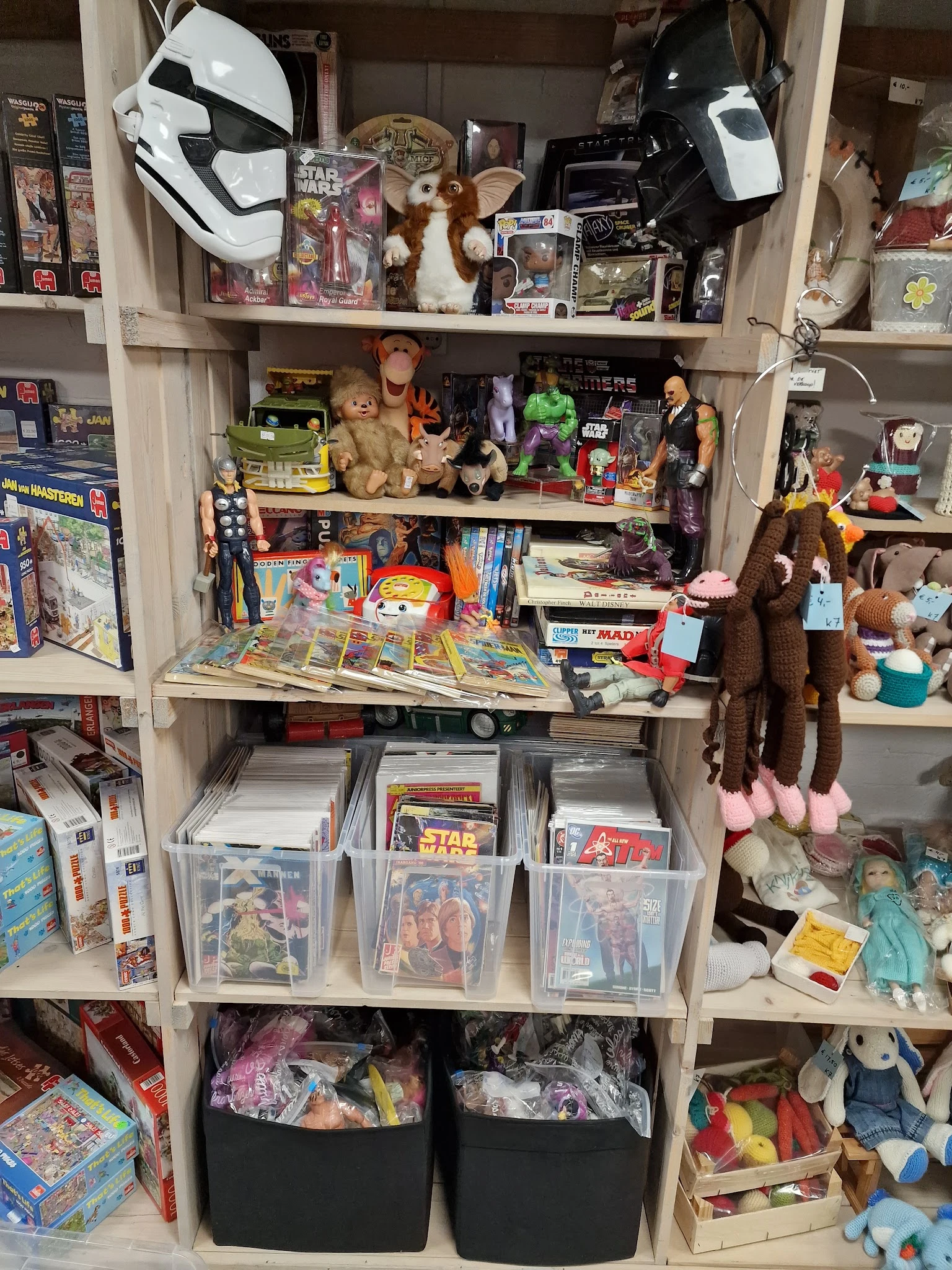Kasten vol verzameld speelgoed, stripboeken, poppen en actiefiguren in de kringloopwinkel