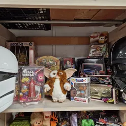 Kastplank met speelgoed en verzamelobjecten: actiefiguren, Gremlins-pop, Star Wars-verpakking en vintage speelgoedauto's