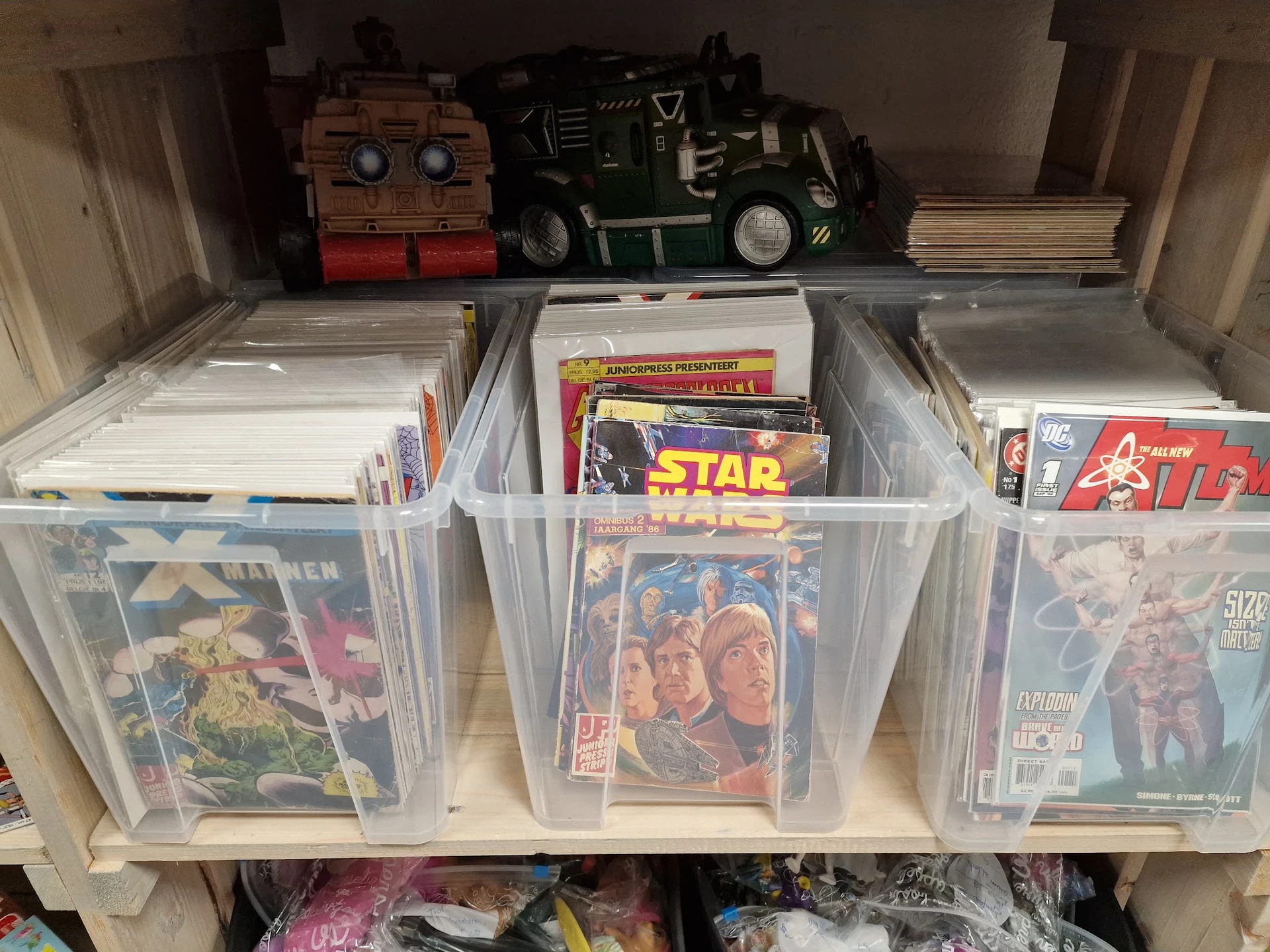Plastic bakken met verzameling strips, stripboeken en comicboeken netjes uitgestald op een plank