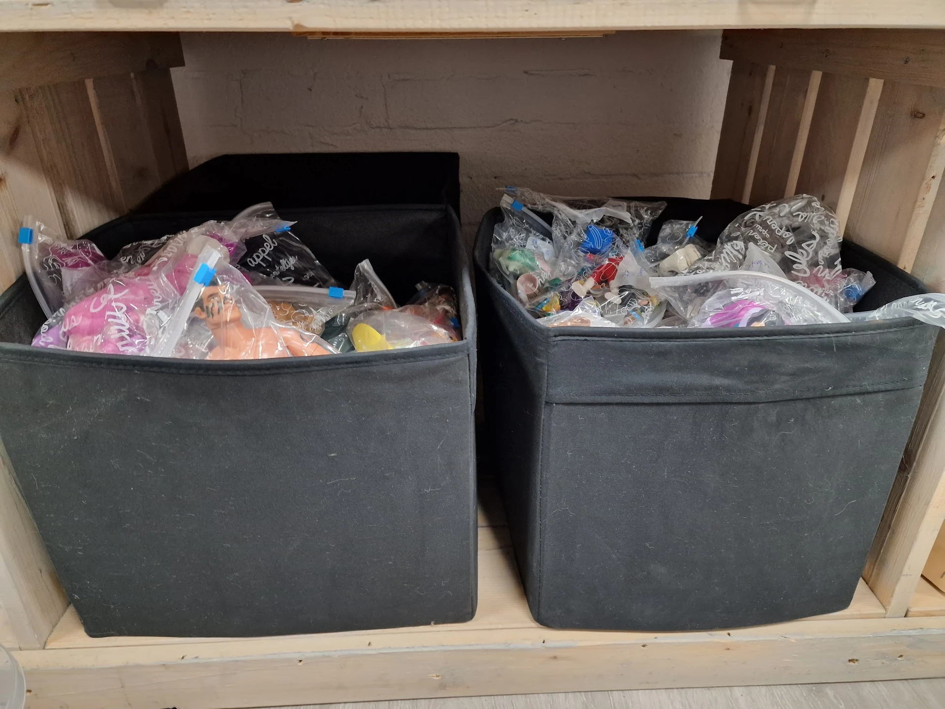 Twee grijze bakken vol met verschillende tweedehands textiel en kleding in een winkelkast