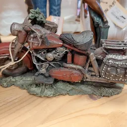 Vintage decoratief motorfietsmodel in rood en bruin met details, op houten tafel