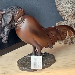 Bronzen beeldje van een vogel op stenen sokkel, met prijskaartje