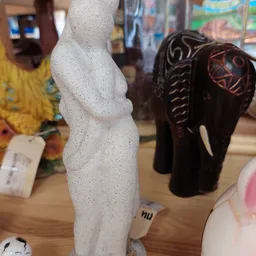 Etalage met decoratieve beelden: witte abstracte sculptuur en bruine houten olifantbeelden met insnijdingen