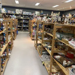 Winkelinterieur met houten stellingen vol collectibles, beeldjes en verzamelaarsartikelen langs beide zijden van het gangpad
