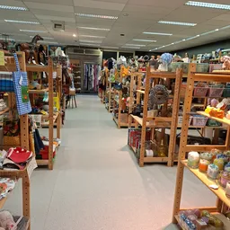 Winkelvloer met houten stellingen vol tweedehands spullen, kleding en huishoudartikelen