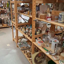 Houten stellingen vol met tweedehands huishoudelijke artikelen, decoratie en verzamelobjecten