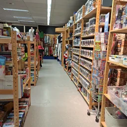 Winkelgang met houten stellingen vol met tweedehands artikelen en merchandise aan beide zijden