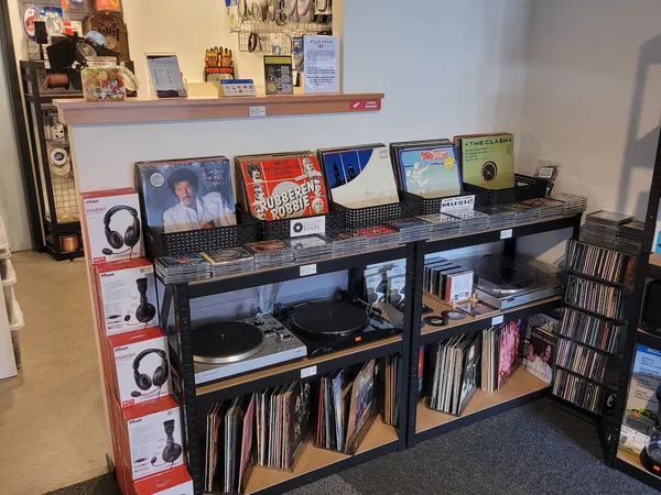 Zwarte werkbank met vinyl records, platenspelers, koptelefoons en media uitgestald