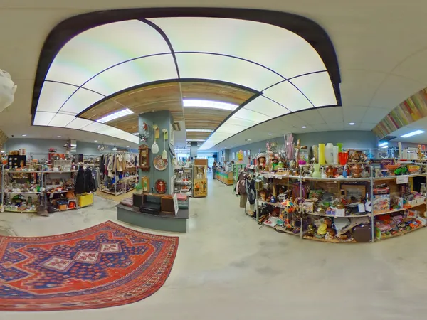 Panoramisch overzicht van de winkelvloer met stellingen, spullen en decorstukken, verlicht door moderne luchtbakken in het pl