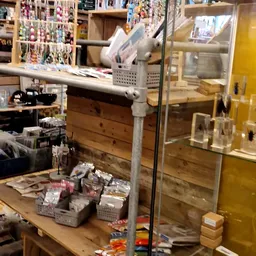 Uitgestalde spullen in manden en dozen op een tafel in de kringloopwinkel, met stellingen en kasten op de achtergrond