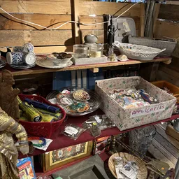 Tweedehands huishoudelijke spullen en decoratieartikelen op tafels, waaronder servies, applicaties en diverse voorwerpen